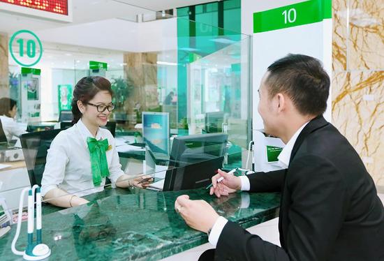 "Khách hàng giao dịch tại quầy giao dịch Vietcombank với nhân viên tận tình hỗ trợ - Dịch vụ ngân hàng uy tín, chuyên nghiệp tại Việt Nam". (Ảnh: ST)